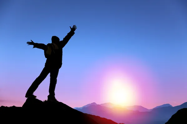 Joven hombre de pie en la cima de la montaña y viendo el amanecer — Foto de Stock