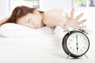 Woman turning off the alarm clock clipart