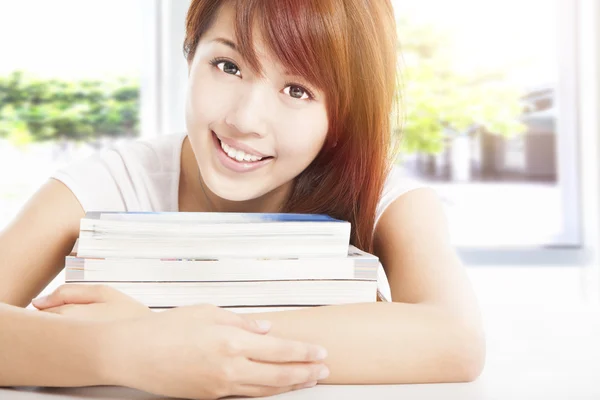 Smiling student holding books in the classroom — Stock Photo, Image