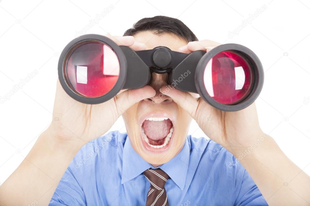 Surprised businessman looks through binoculars and isolated