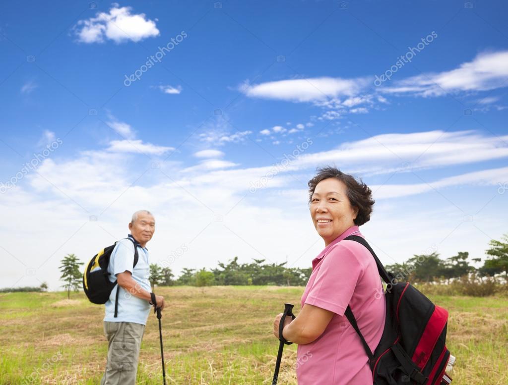 Happy asian senior couple hiking in the nature