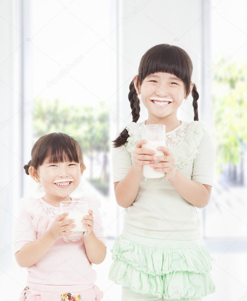 Two little girls holding a glass of fresh milk