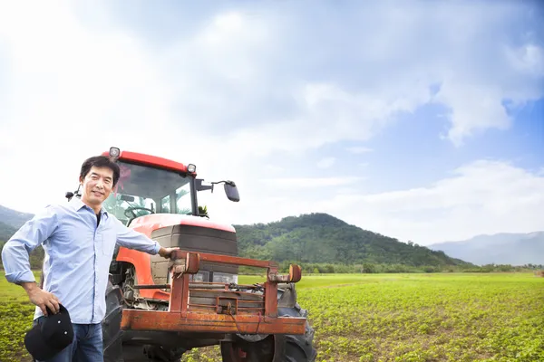 Šťastné asijské farmář s starý traktor na louky — Stock fotografie