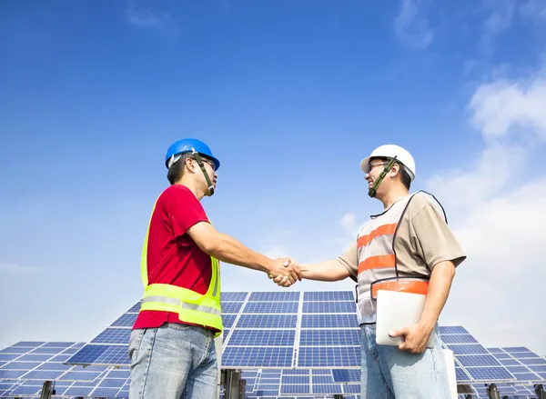 Zwei Ingenieure beim Händeschütteln vor großem Solarkraftwerk — Stockfoto