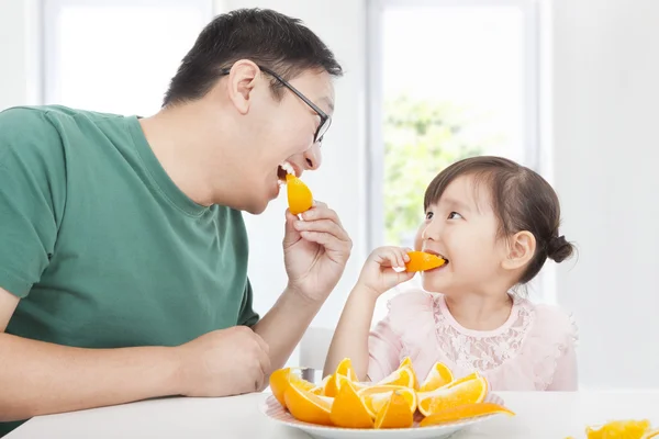 Bonne petite fille avec père mangeant orange — Photo