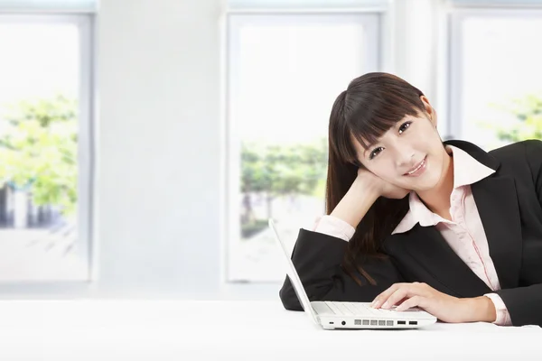 Sorrindo jovem empresária com laptop no escritório — Fotografia de Stock