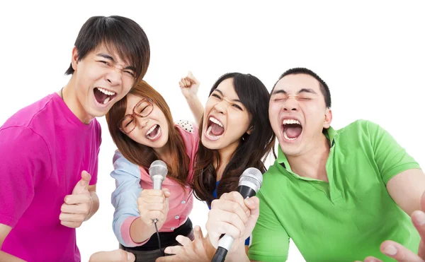 Grupo jovem feliz se divertindo cantando com karaoke — Fotografia de Stock