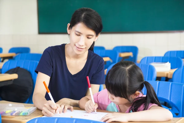 Mère enseignant petite fille dessin image dans la salle de classe — Photo