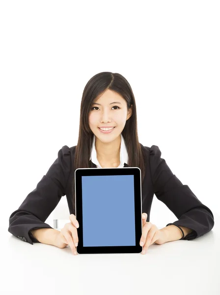 Улыбающаяся молодая деловая женщина, показывающая планшетный компьютер на столе — стоковое фото
