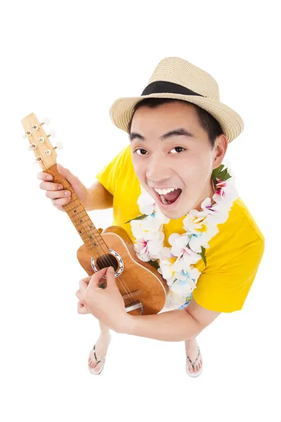 Молодой человек играет на укулеле и поет — стоковое фото