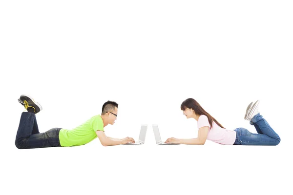 Felice giovane coppia sdraiata insieme con il computer portatile — Foto Stock