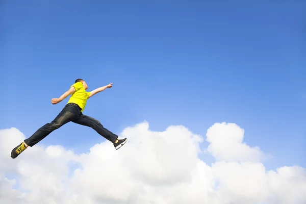 Jovem feliz pulando e apontando para o céu — Fotografia de Stock