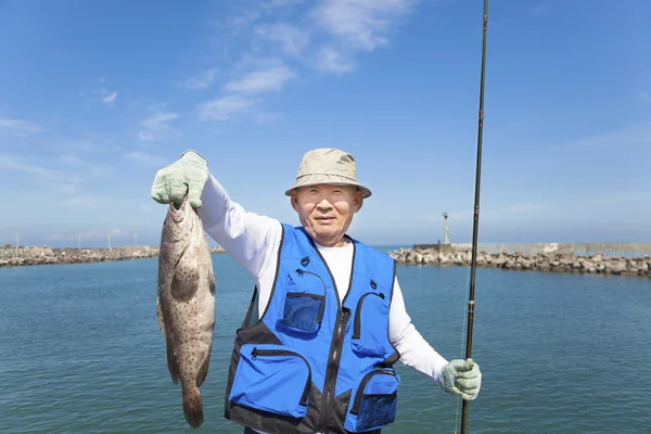 Happy asian senior fisherman showing large grouper — Stock Photo, Image