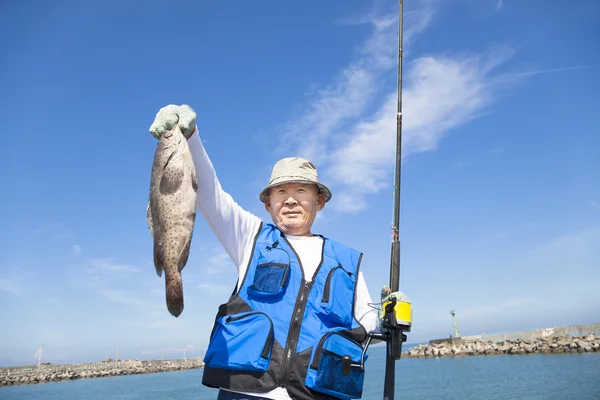 Happy senior fisherman showing large grouper — Stock Photo, Image