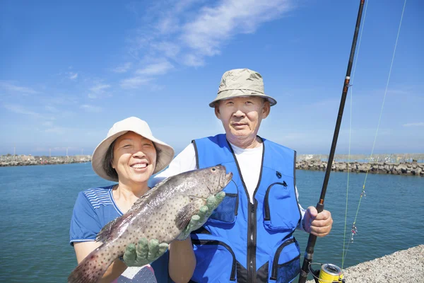 Happy senior couple go fishing and showing big fish — Stock Photo, Image