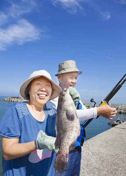 Happy senior couple fishing and showing big grouper fish — Stock Photo, Image