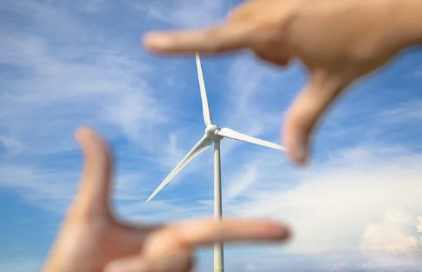 Olhando para o gerador de energia do moinho de vento com moldura da mão — Fotografia de Stock