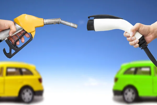 Elektrické auto a benzín auto koncept. ruka držící benzinové pumpy a — Stock fotografie