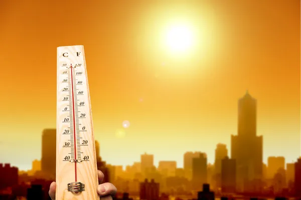 Ola de calor en la ciudad y mano mostrando termómetro para alta temperatura —  Fotos de Stock