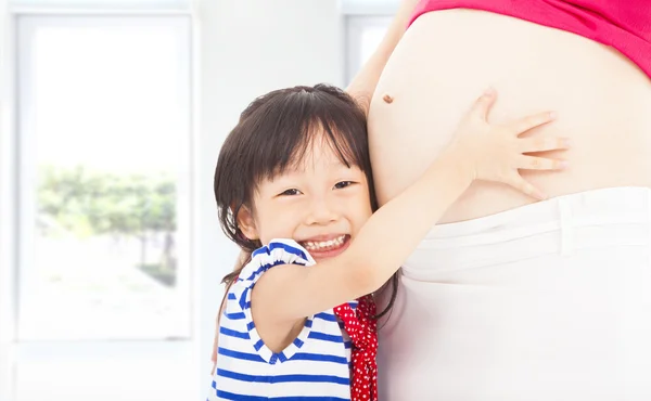 Menina feliz abraçando a barriga de uma mãe grávida — Fotografia de Stock