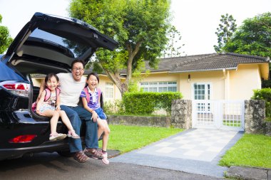 happy family sitting in the car and their house behind clipart