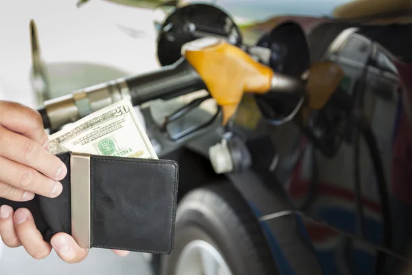 Hombre contando dinero con gasolina repostando coche en la gasolinera — Foto de Stock