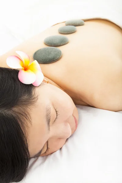 Mulher relaxada no salão de spa com pedras — Fotografia de Stock