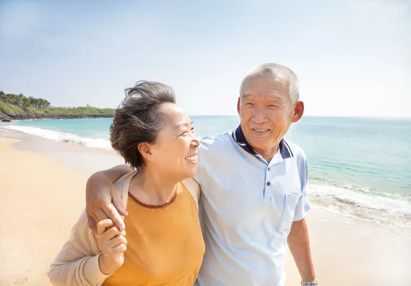 在沙滩上散步的快乐亚洲老年人 免版税图库照片