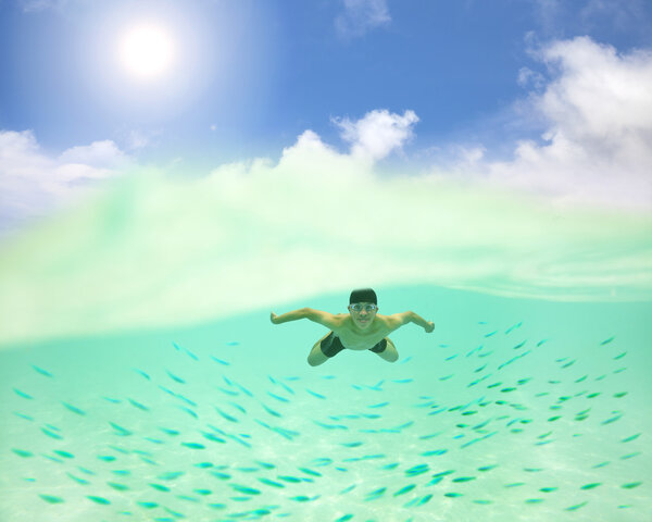 young man swimming undersea with fishes