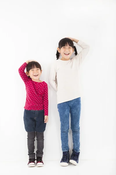 Glückliche Kinder stehen vor weißer Wand — Stockfoto