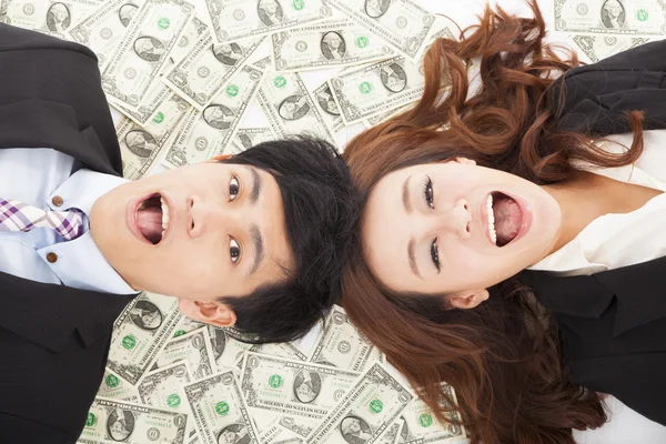 Surprised businessman and woman lying on the money — Stock Photo, Image