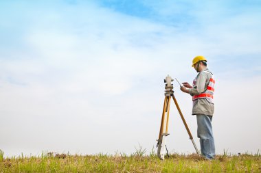 Surveyor engineer making measure on the field with tablet pc clipart