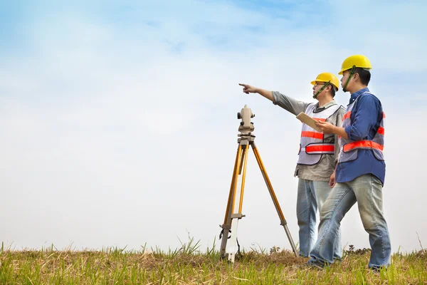 Ingeniero topógrafo haciendo medida con socio en el campo —  Fotos de Stock