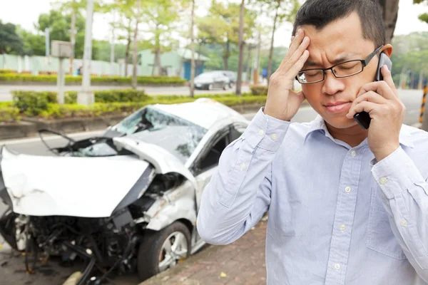 Расстроенный водитель разговаривает по мобильному телефону с аварийной машиной — стоковое фото