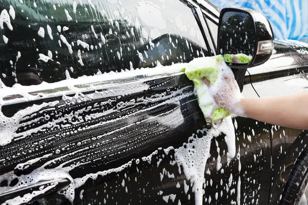 Mani tenere spugna per il lavaggio auto Fotografia Stock