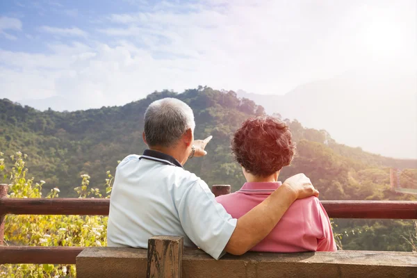 Старша пара сидить на лавці, дивлячись на краєвид на природу — стокове фото