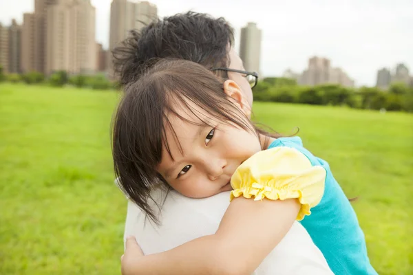 Улыбающаяся маленькая девочка на плече отца в городском парке — стоковое фото