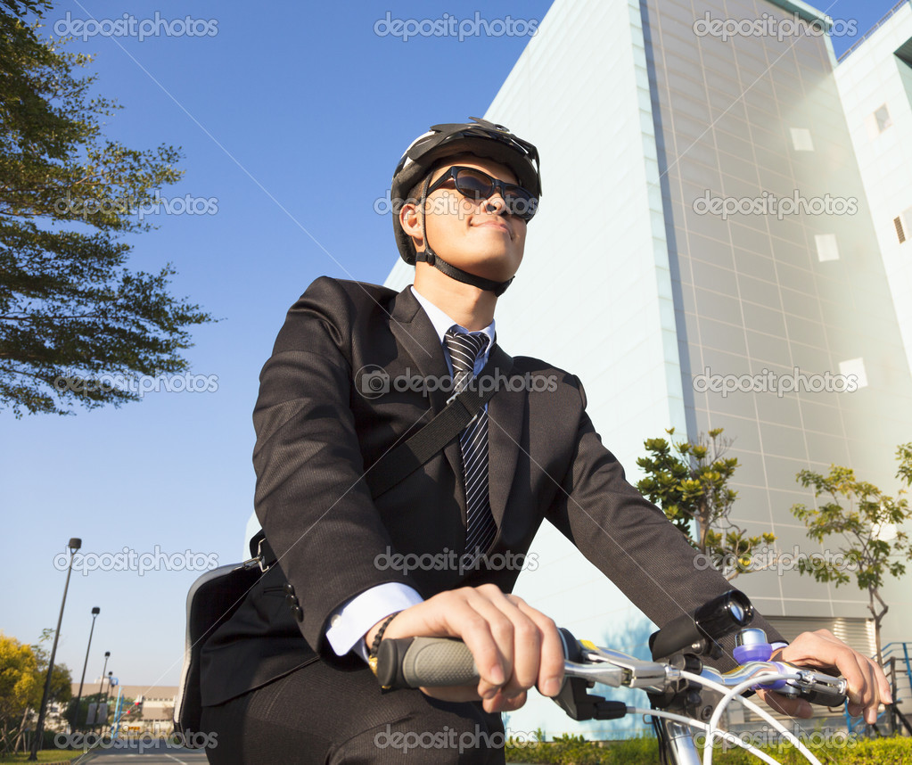 Businessman riding a bicycle to workplace in exteior building