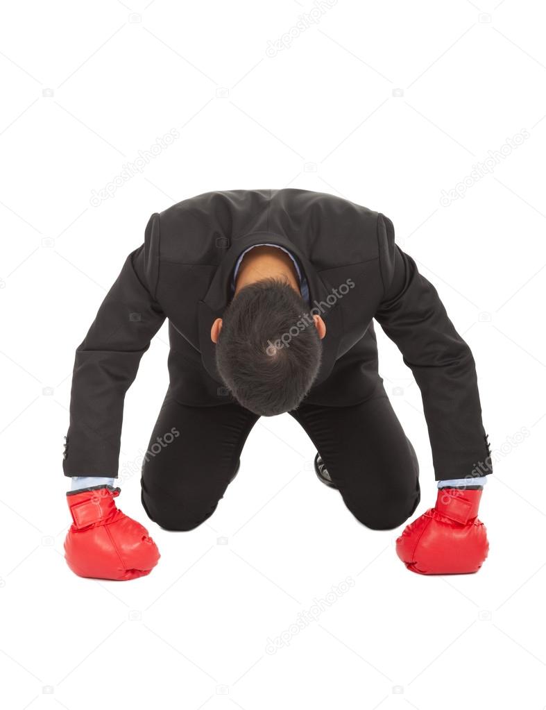 Businessman losed with boxing glove on sneeling position.