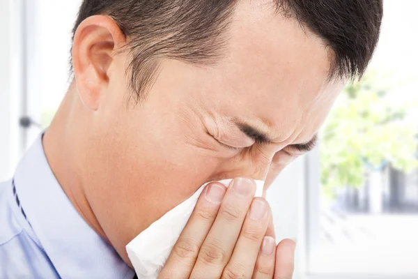 Young man is sneezing with toilet paper — Stock Image Young man is sneezing with toilet paper Stock Picture