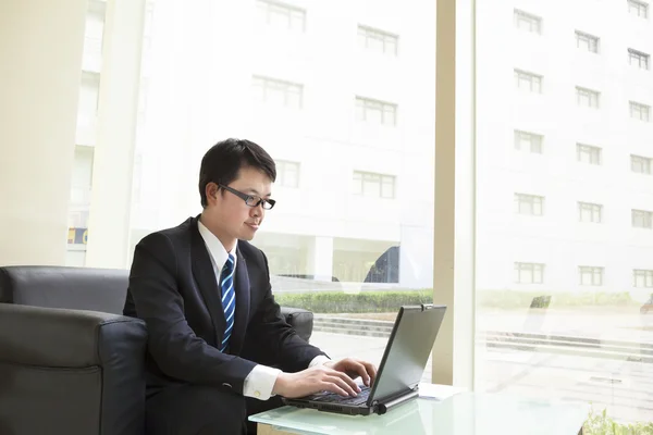 Geschäftsmann sitzt in hellem Büro und arbeitet am Laptop — Stockfoto