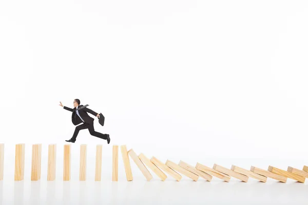 Homem de negócios correndo e pegando no derrubar dominós — Fotografia de Stock