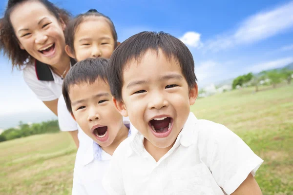 Asiática sonriente familia jugando en prado y soleado día — Foto de Stock