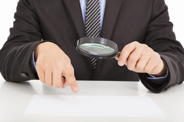 Businessman pointing through a magnifying glass to documents — Stock Photo, Image