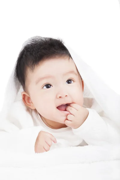 Sorrindo bebê chupando o dedo sob cobertor ou toalha — Fotografia de Stock