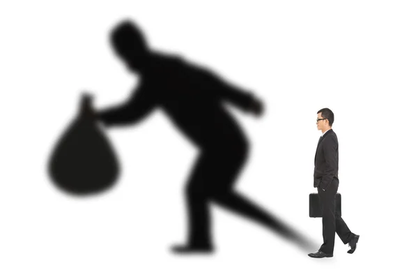 Businessman walking and holding bag with thief shadow — Stock Photo, Image