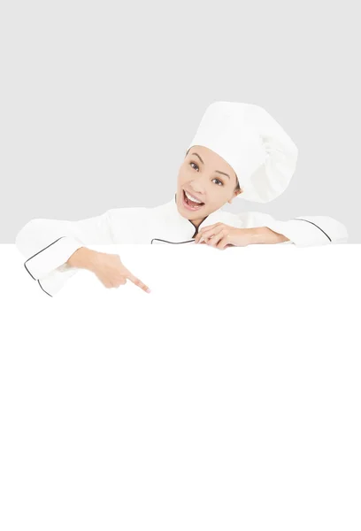 Smiling young woman chef pointing with blank board — Stock Photo, Image