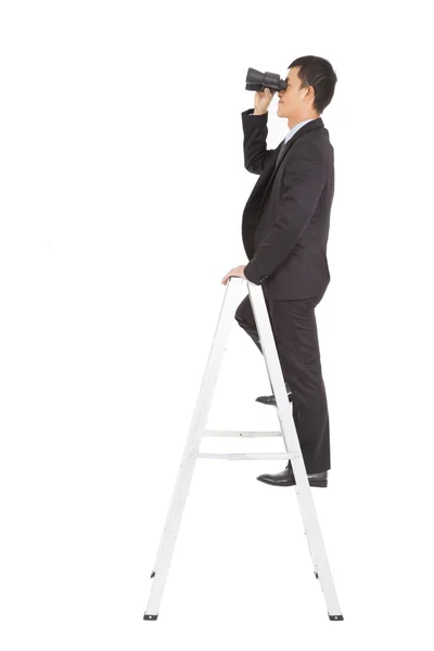 Businessman using a pair of binoculars standing on stair — Stock Photo, Image