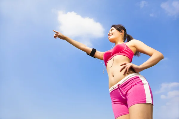 Asian smiling sporty woman watching and pointing far away — Stock Photo, Image