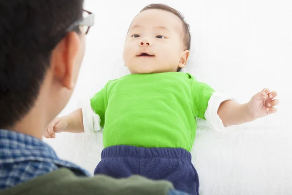 Young happy father playing with baby lying in bed — Stock Photo, Image
